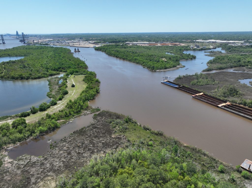 A photograph taken by drone of Chickasaw Creek and Hog Bayou looking south towards the Africatown Bridge and downtown Mobile, visible in the background.